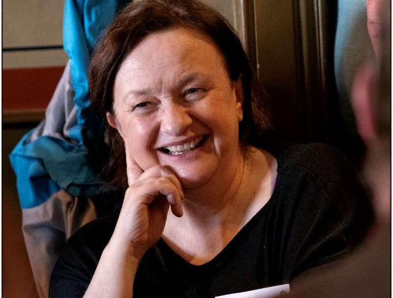 Grace Toland a woman with dark hair sits in a chair smiling