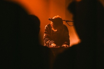 A musician plays a keyboard on a dimly lit stage for an audience