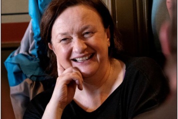 Grace Toland a woman with dark hair sits in a chair smiling