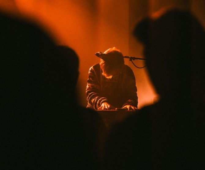 A musician plays a keyboard on a dimly lit stage for an audience